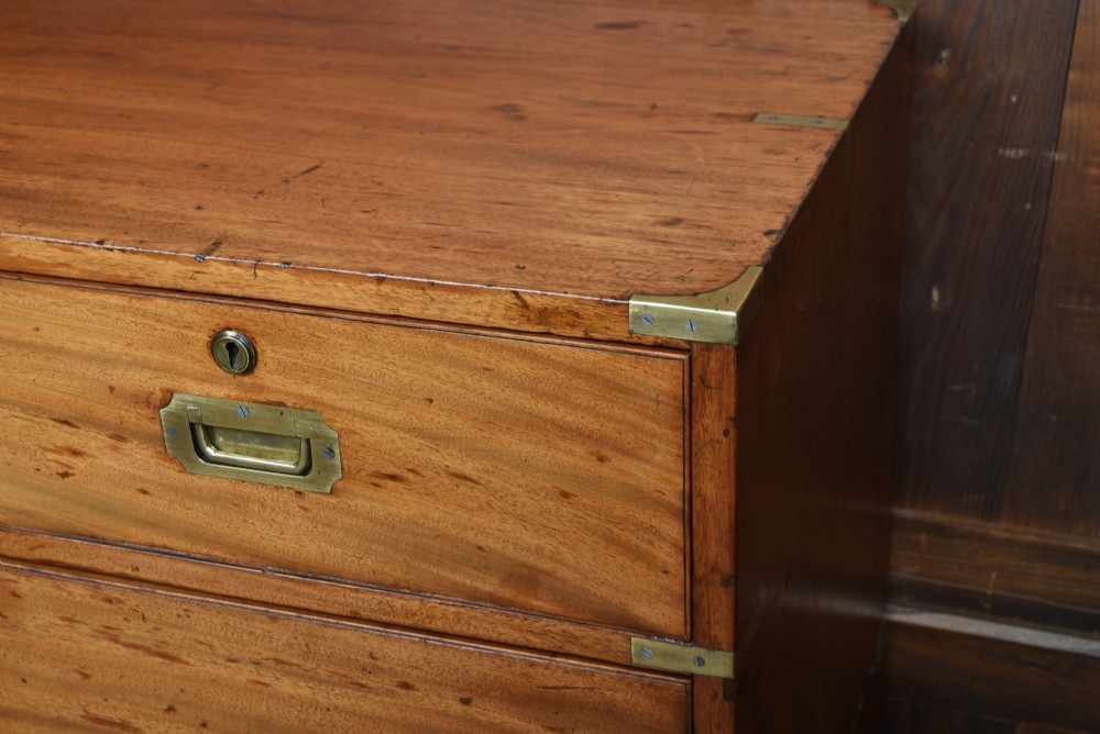 A 19th-century mahogany campaign chest of drawers with two short over three long drawers, featuring inset brass handles and brass corner straps. View VI