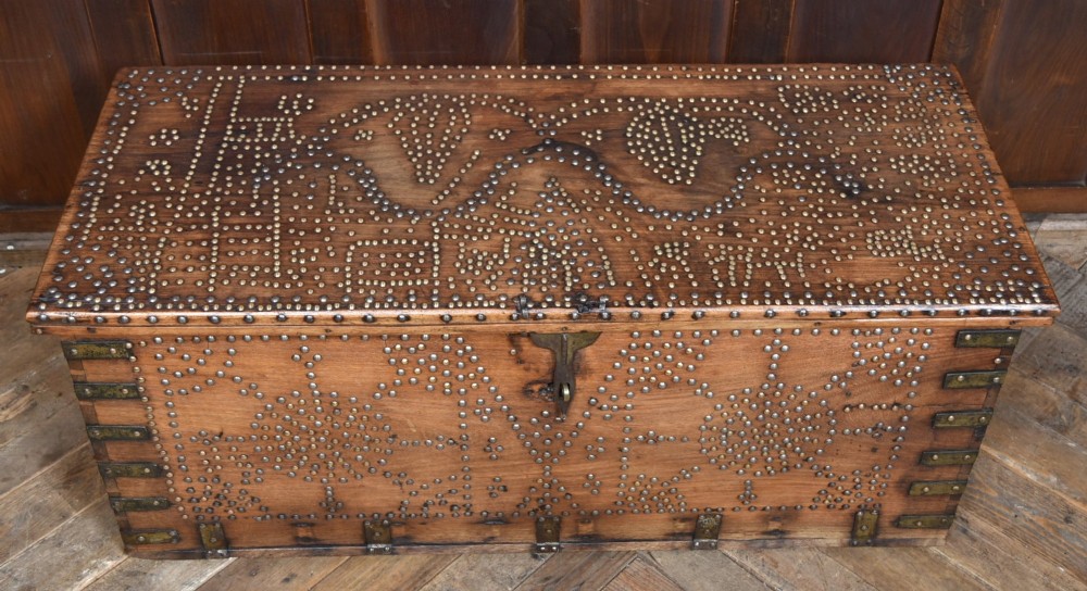 A solid padouk wood rectangular blanket box featuring intricate geometric brass stud patterns and metal strap reinforcements. View III