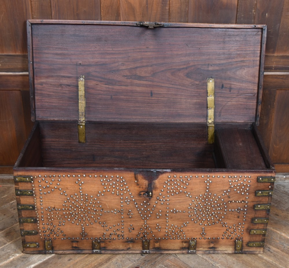 A solid padouk wood rectangular blanket box featuring intricate geometric brass stud patterns and metal strap reinforcements. View VIII