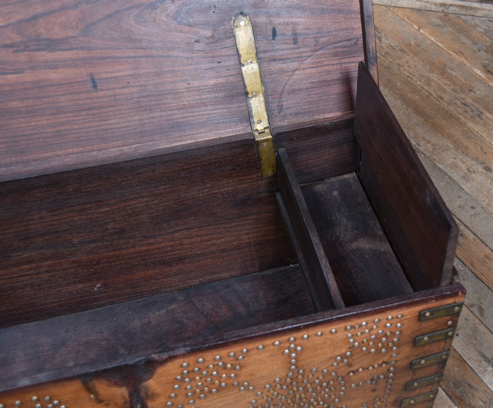 A solid padouk wood rectangular blanket box featuring intricate geometric brass stud patterns and metal strap reinforcements. View X