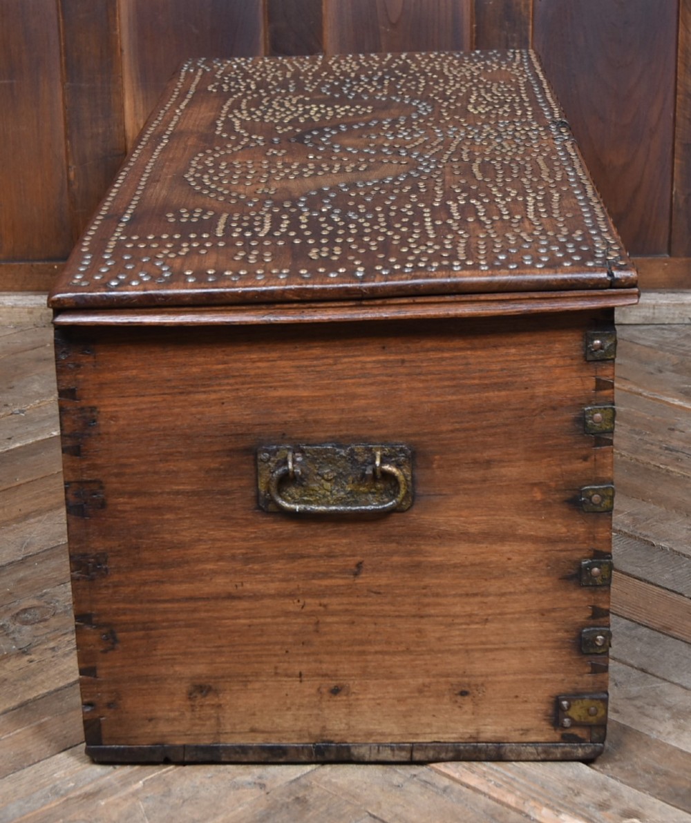 A solid padouk wood rectangular blanket box featuring intricate geometric brass stud patterns and metal strap reinforcements. View XII
