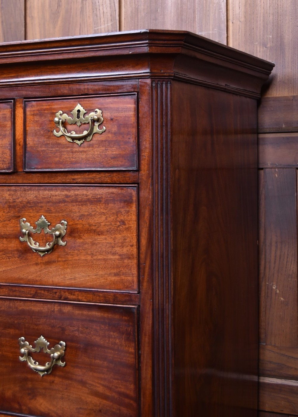 A tall Georgian mahogany chest on chest featuring two stacked tiers of drawers with brass swan-neck handles resting on bracket feet. View II