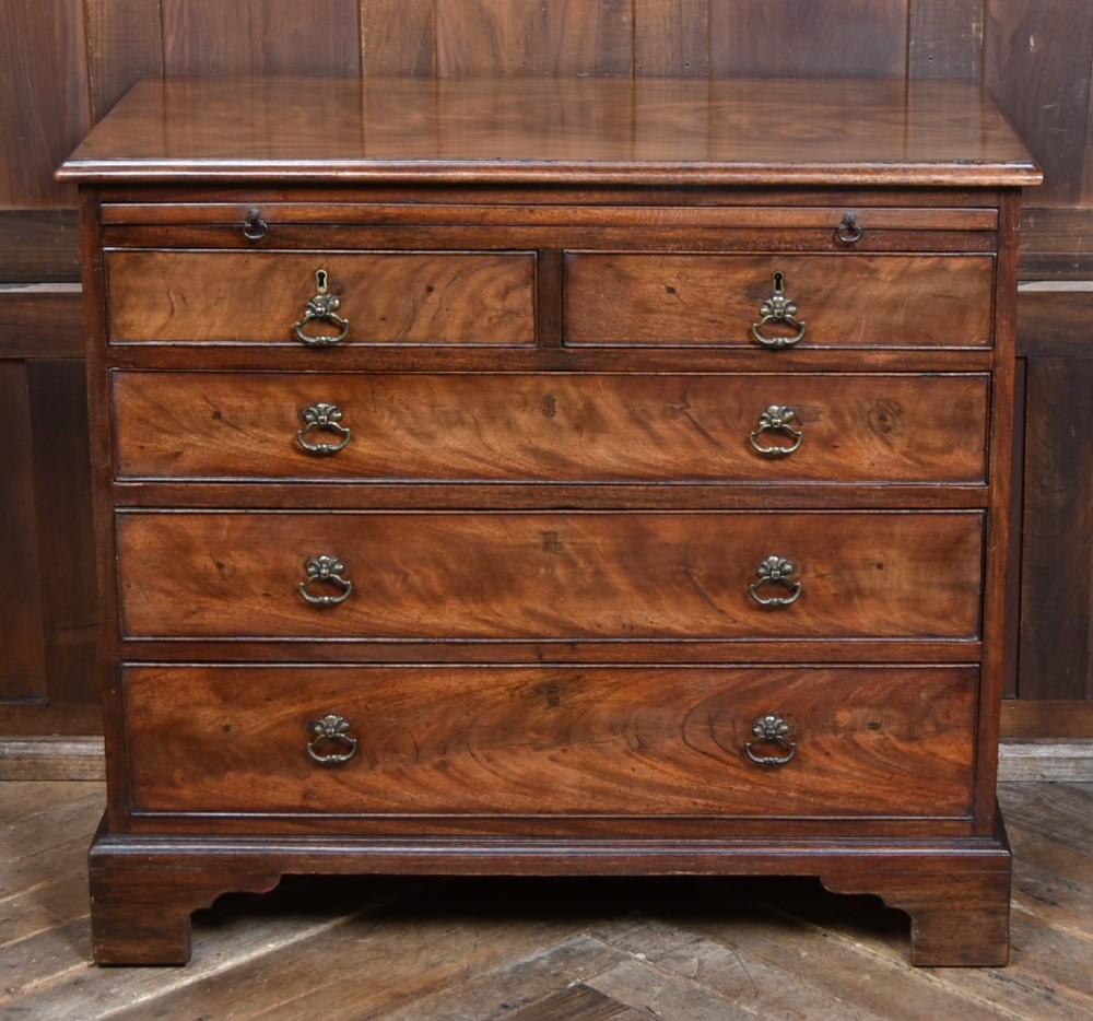 An 18th-century Georgian mahogany chest of drawers with a pull-out brushing slide, two short over three long graduated drawers, brass bail handles, and bracket feet. View II