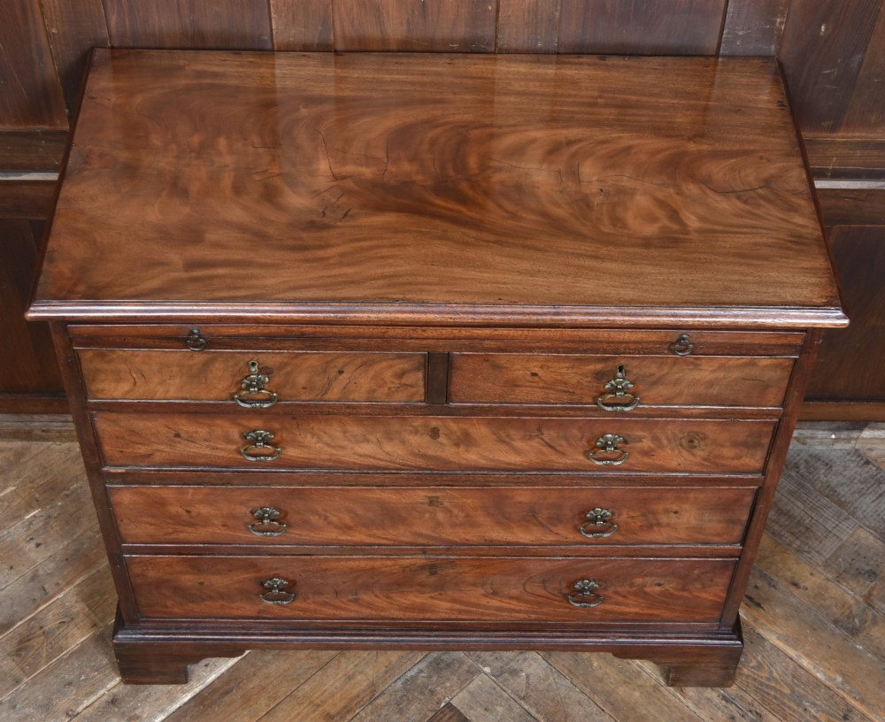 An 18th-century Georgian mahogany chest of drawers with a pull-out brushing slide, two short over three long graduated drawers, brass bail handles, and bracket feet. View III