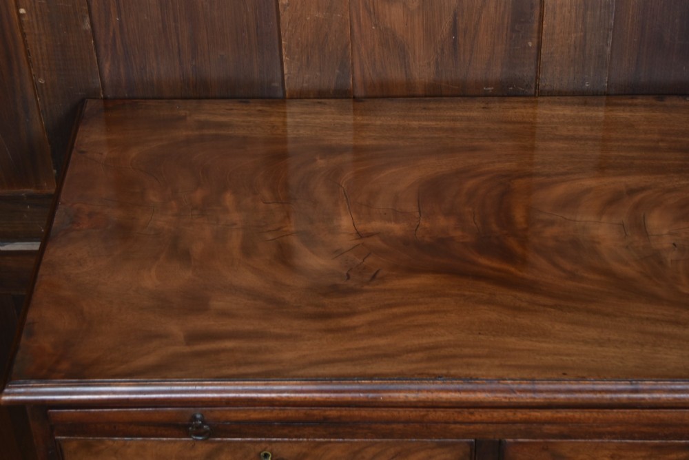An 18th-century Georgian mahogany chest of drawers with a pull-out brushing slide, two short over three long graduated drawers, brass bail handles, and bracket feet. View IV