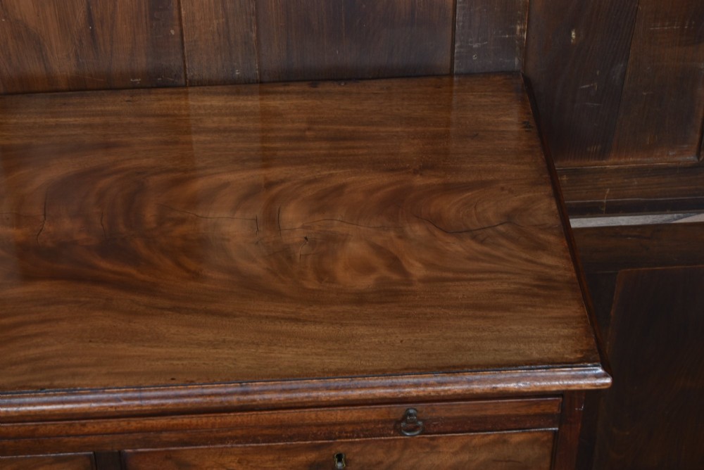 An 18th-century Georgian mahogany chest of drawers with a pull-out brushing slide, two short over three long graduated drawers, brass bail handles, and bracket feet. View V