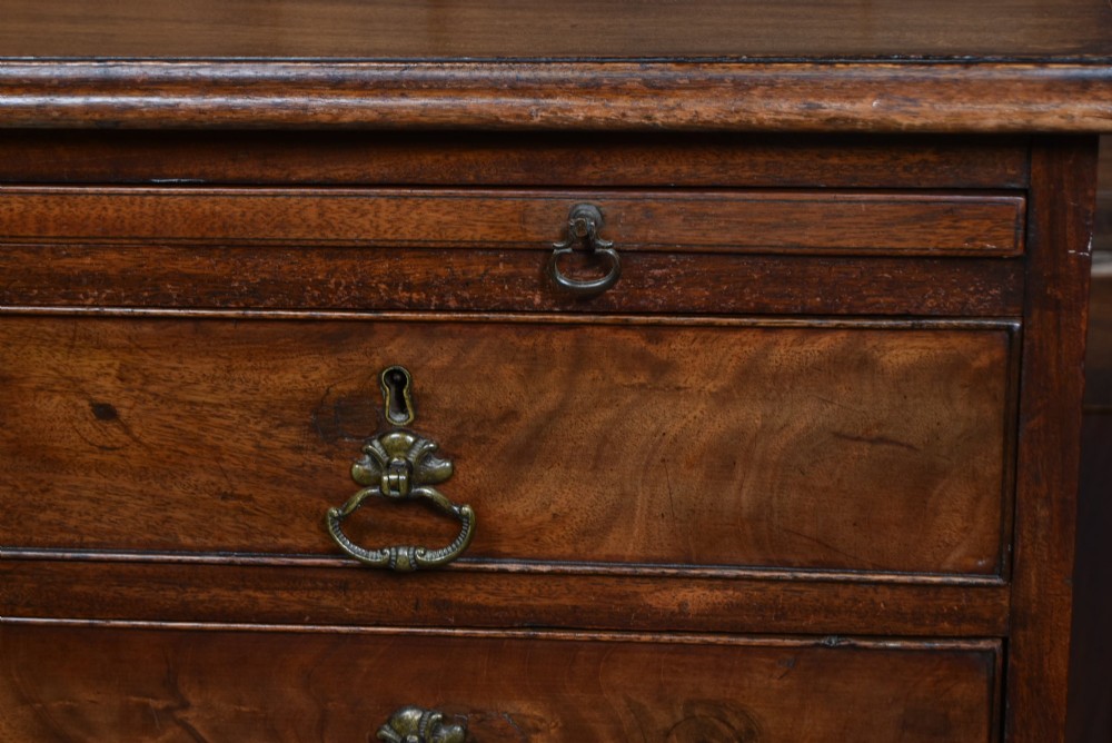 An 18th-century Georgian mahogany chest of drawers with a pull-out brushing slide, two short over three long graduated drawers, brass bail handles, and bracket feet. View VI