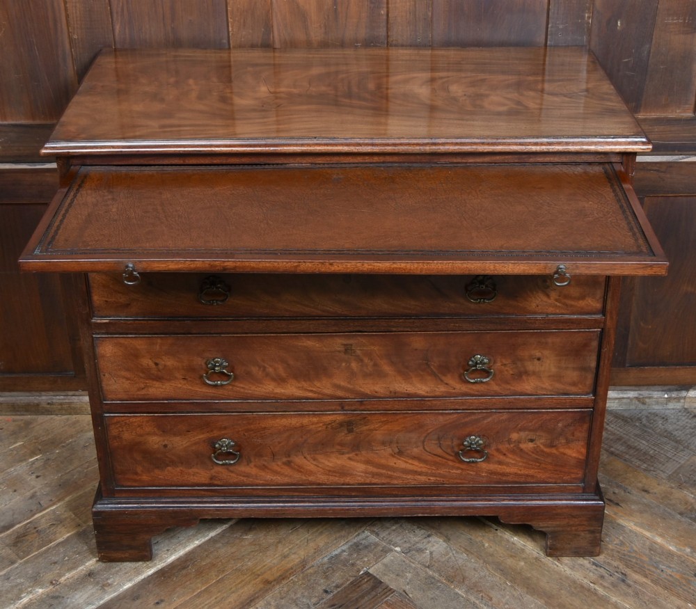 An 18th-century Georgian mahogany chest of drawers with a pull-out brushing slide, two short over three long graduated drawers, brass bail handles, and bracket feet. View VII