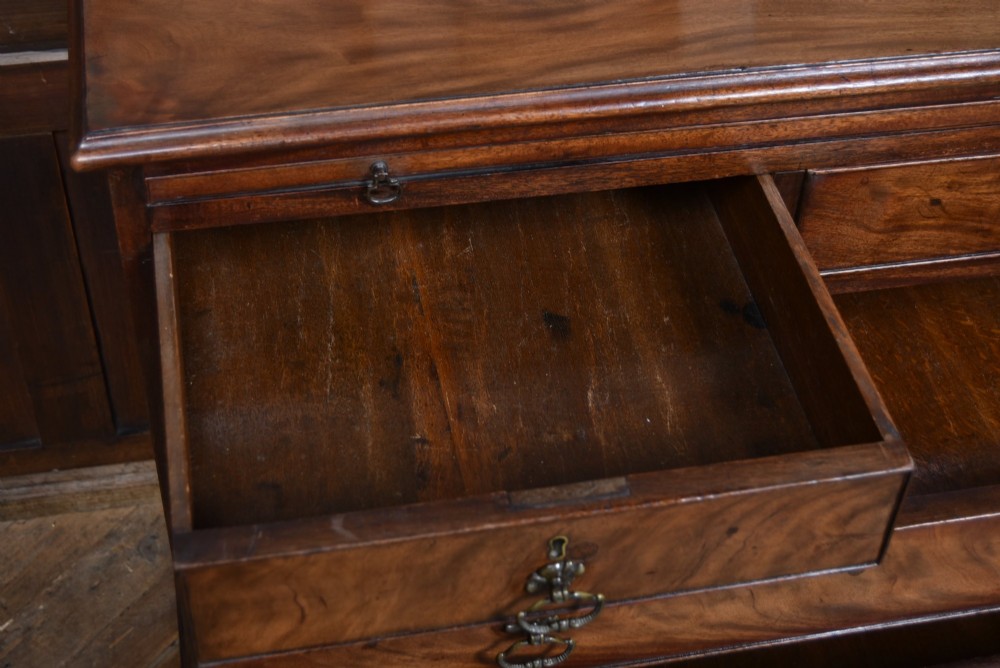 An 18th-century Georgian mahogany chest of drawers with a pull-out brushing slide, two short over three long graduated drawers, brass bail handles, and bracket feet. View X