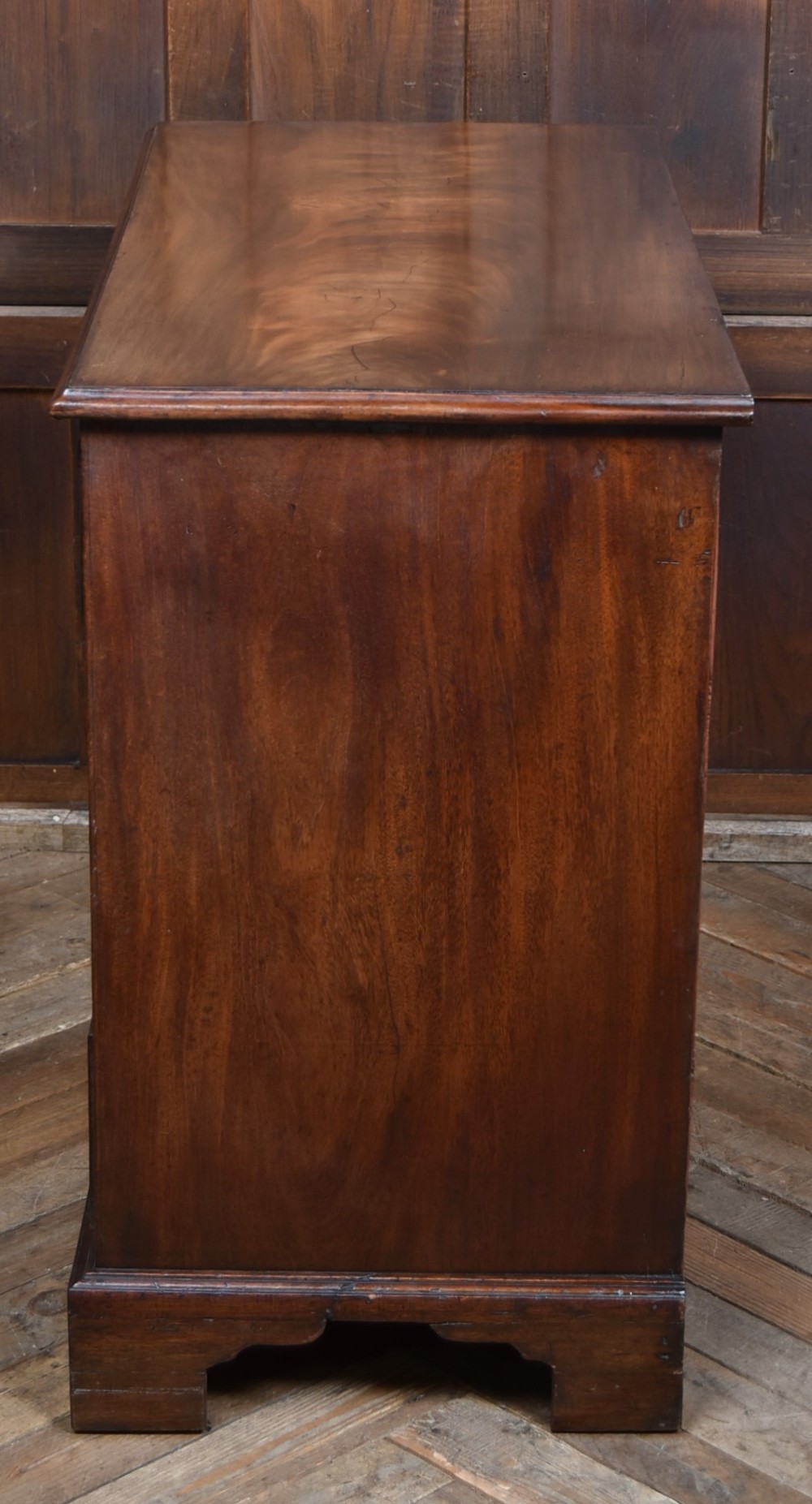 An 18th-century Georgian mahogany chest of drawers with a pull-out brushing slide, two short over three long graduated drawers, brass bail handles, and bracket feet. View XIII
