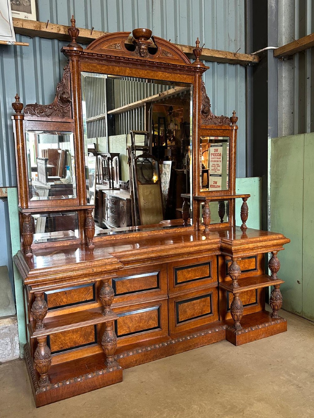 A large Victorian pollard oak mirror-back sideboard featuring carved urn finials, central mirror glass, open side shelving, and ebonised drawer borders.