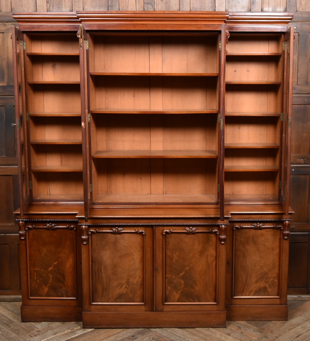 A large Victorian mahogany breakfront bookcase featuring four glazed upper doors and four panelled lower cupboard doors with carved details. View II