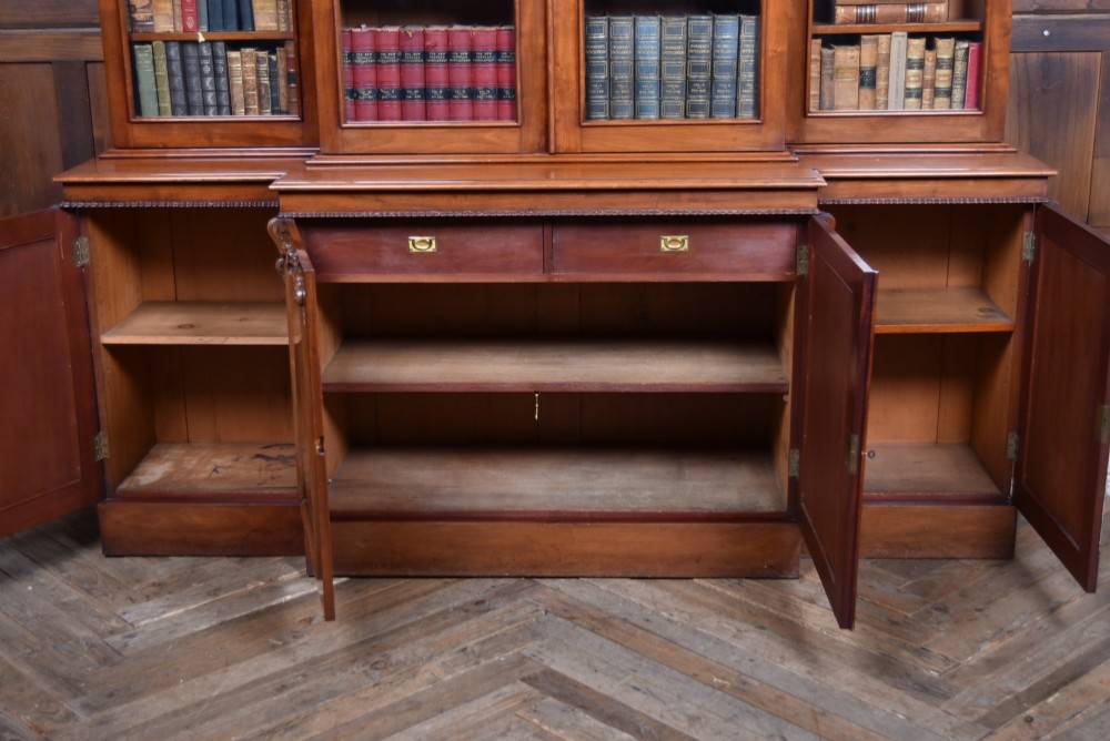 A large Victorian mahogany breakfront bookcase featuring four glazed upper doors and four panelled lower cupboard doors with carved details. View III