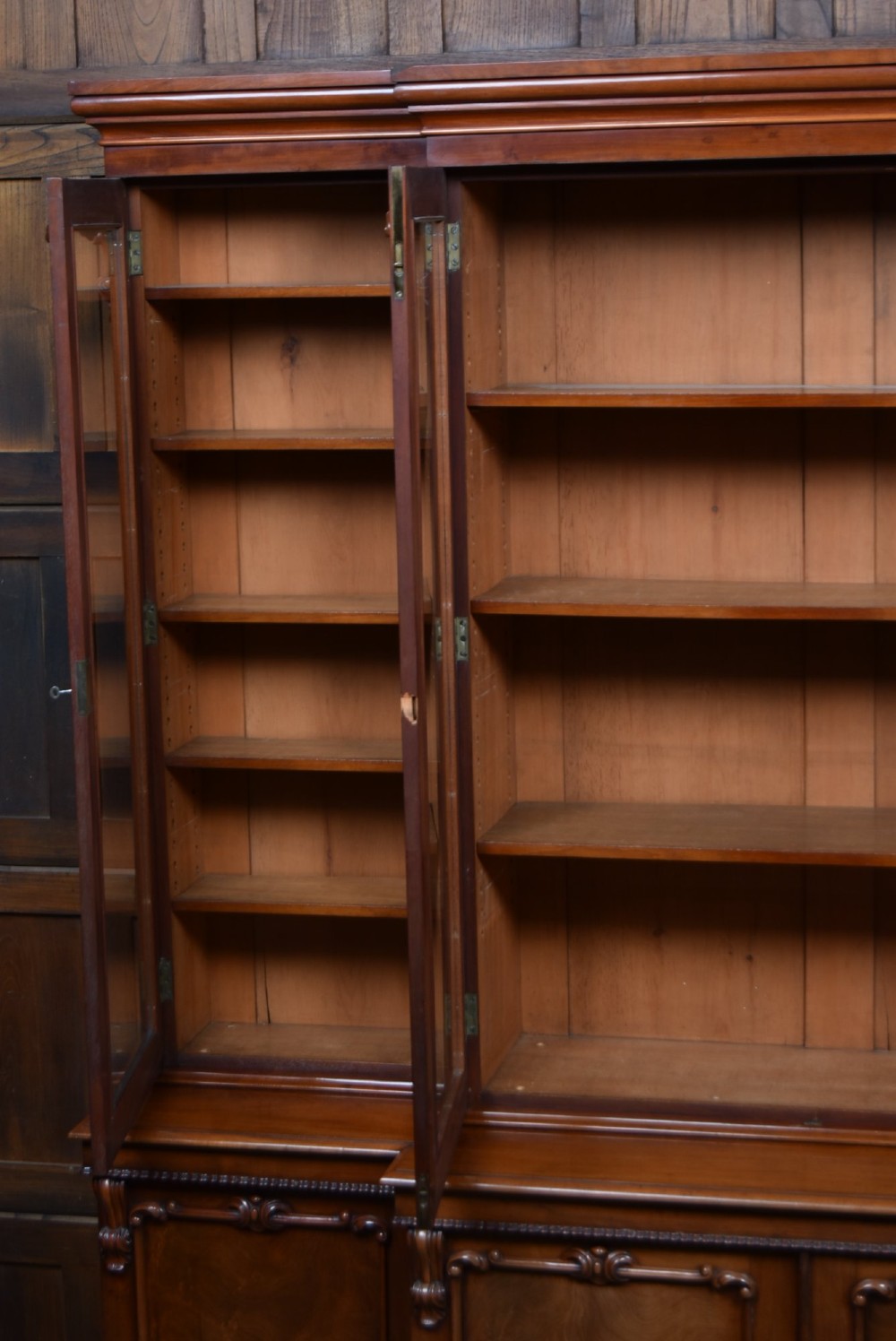A large Victorian mahogany breakfront bookcase featuring four glazed upper doors and four panelled lower cupboard doors with carved details. View VII