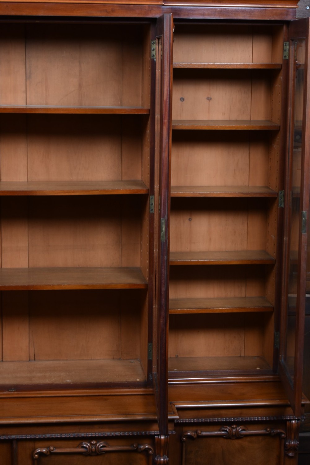 A large Victorian mahogany breakfront bookcase featuring four glazed upper doors and four panelled lower cupboard doors with carved details. View VIII