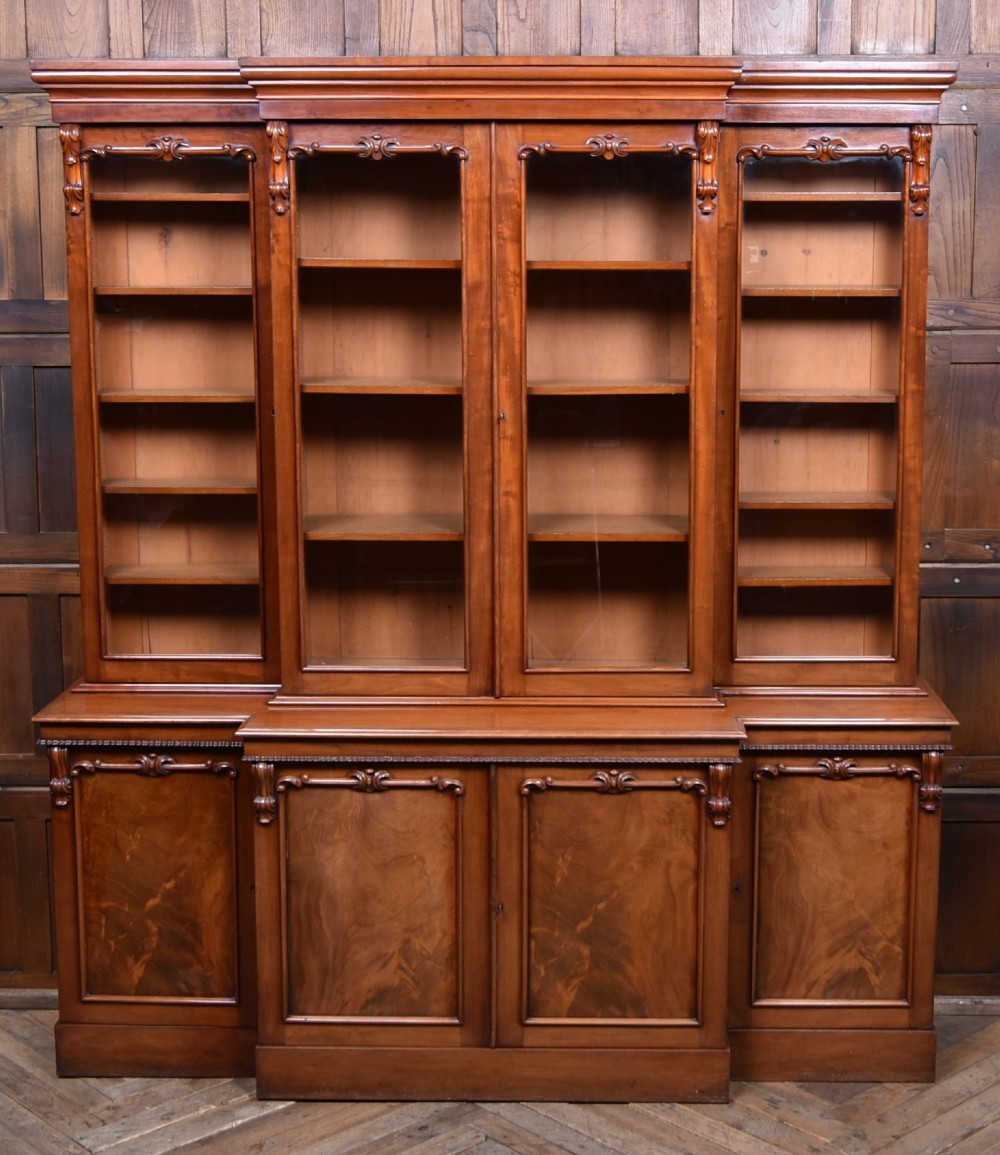 A large Victorian mahogany breakfront bookcase featuring four glazed upper doors and four panelled lower cupboard doors with carved details. View IX