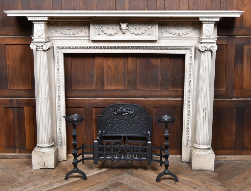 An off-white painted Neoclassical fireplace surround featuring fluted columns and swags, paired with a black cast iron fire grate.