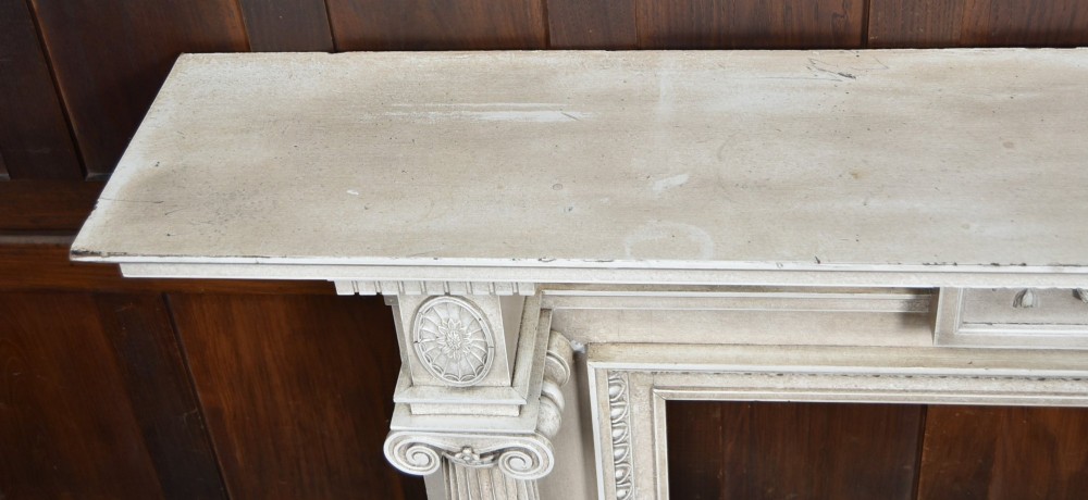An off-white painted Neoclassical fireplace surround featuring fluted columns and swags, paired with a black cast iron fire grate. View XIII