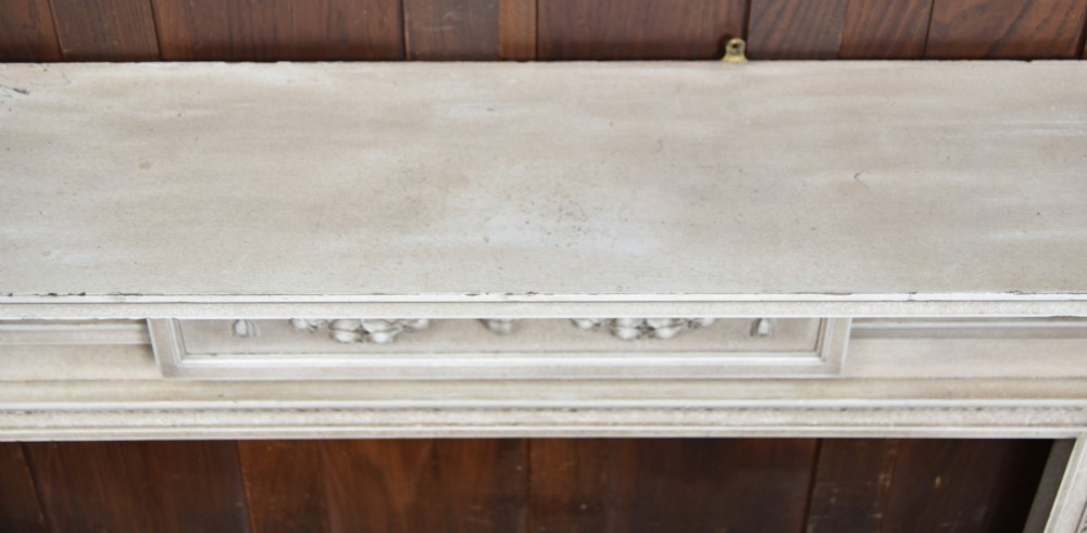 An off-white painted Neoclassical fireplace surround featuring fluted columns and swags, paired with a black cast iron fire grate. View XIV
