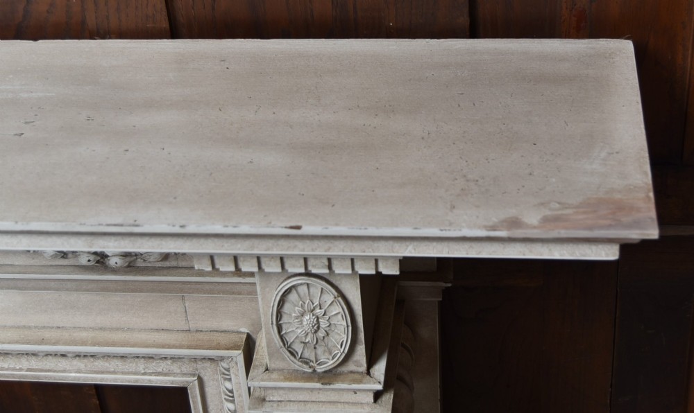 An off-white painted Neoclassical fireplace surround featuring fluted columns and swags, paired with a black cast iron fire grate. View XV