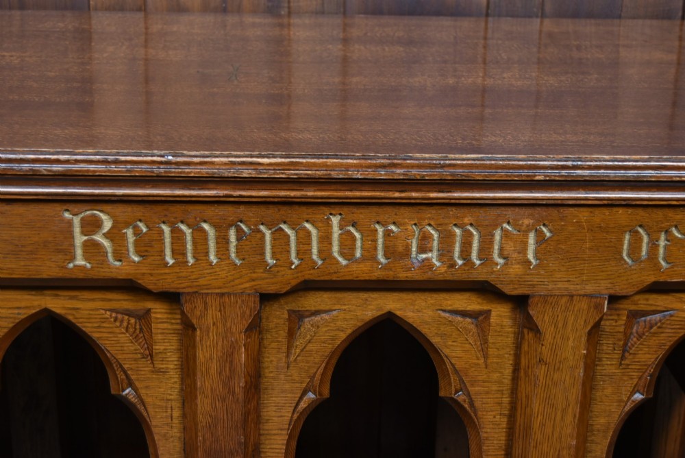 A Victorian oak church communion table with carved Gothic arch panels and a carved inscription reading Do this in Remembrance of me along the top frieze. View III
