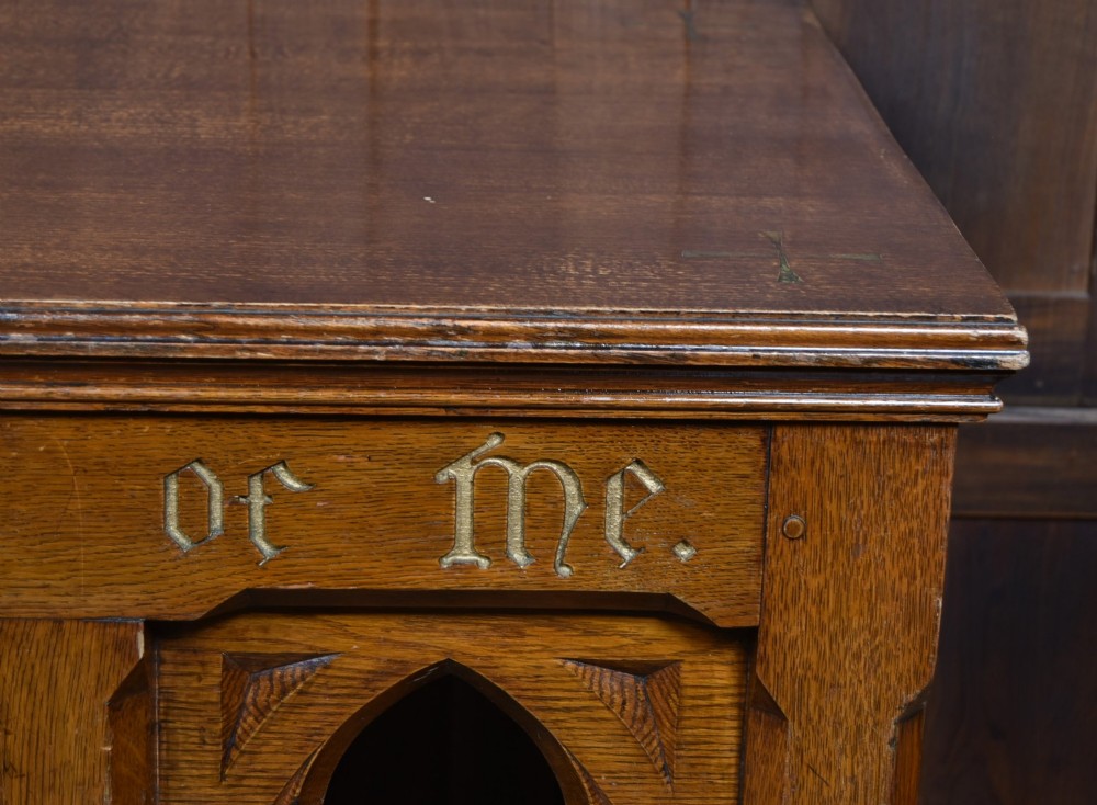 A Victorian oak church communion table with carved Gothic arch panels and a carved inscription reading Do this in Remembrance of me along the top frieze. View IV