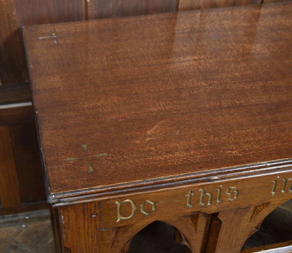 A Victorian oak church communion table with carved Gothic arch panels and a carved inscription reading Do this in Remembrance of me along the top frieze. View VIII