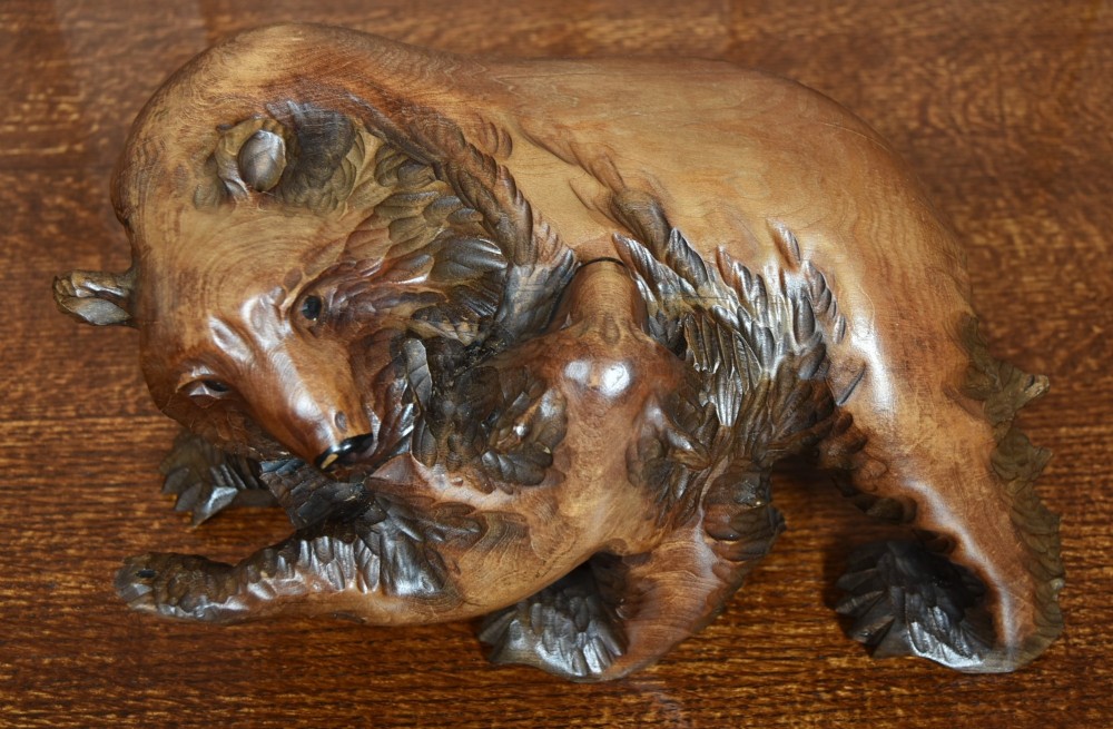 A hand-carved warm brown wooden sculpture depicting a mother bear with a cub clinging to her side. View III