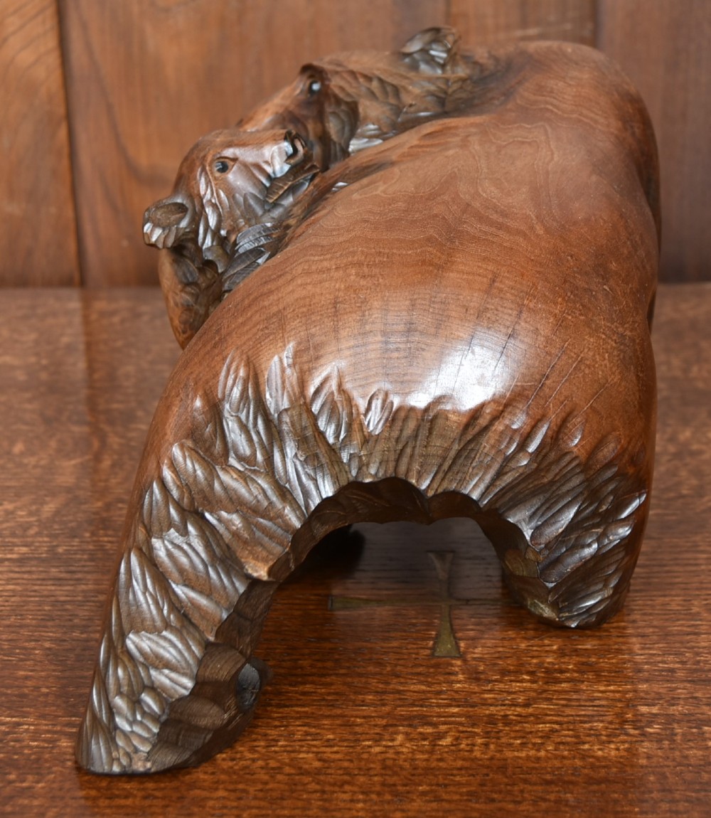 A hand-carved warm brown wooden sculpture depicting a mother bear with a cub clinging to her side. View VII