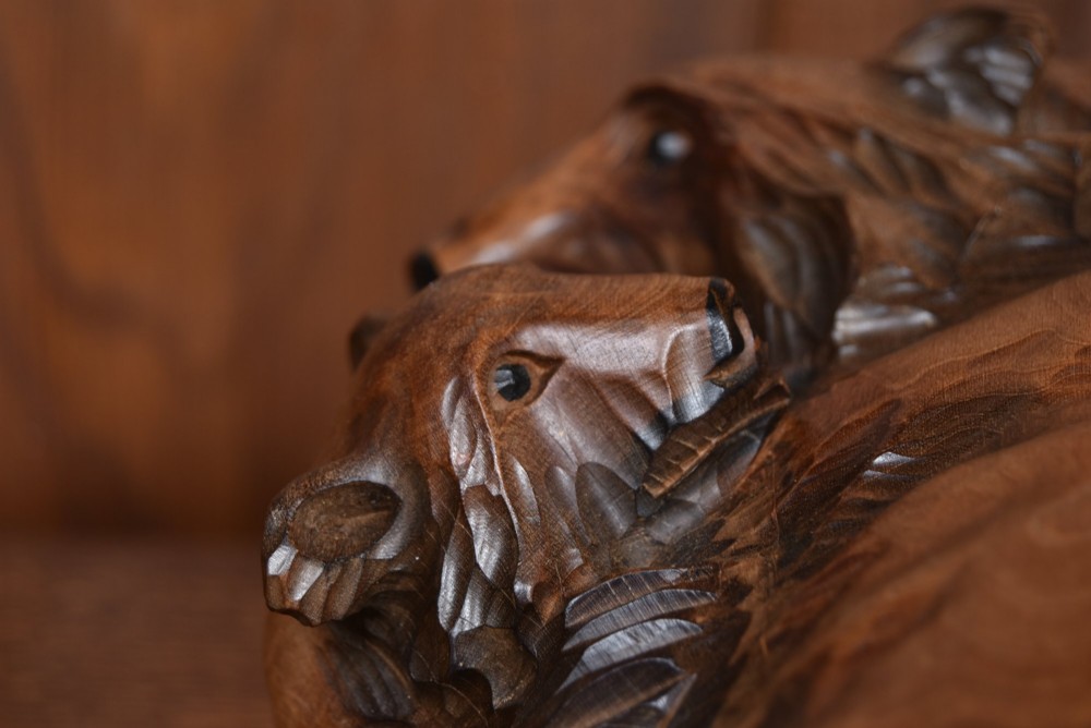 A hand-carved warm brown wooden sculpture depicting a mother bear with a cub clinging to her side. View VIII