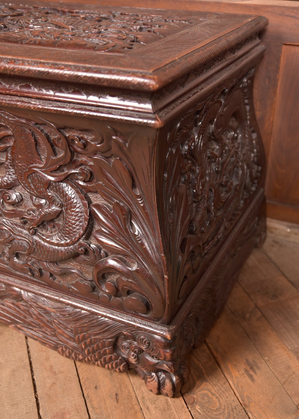 A dark brown rectangular carved hardwood storage chest decorated with high-relief dragon and cloud motifs on all visible faces. View III