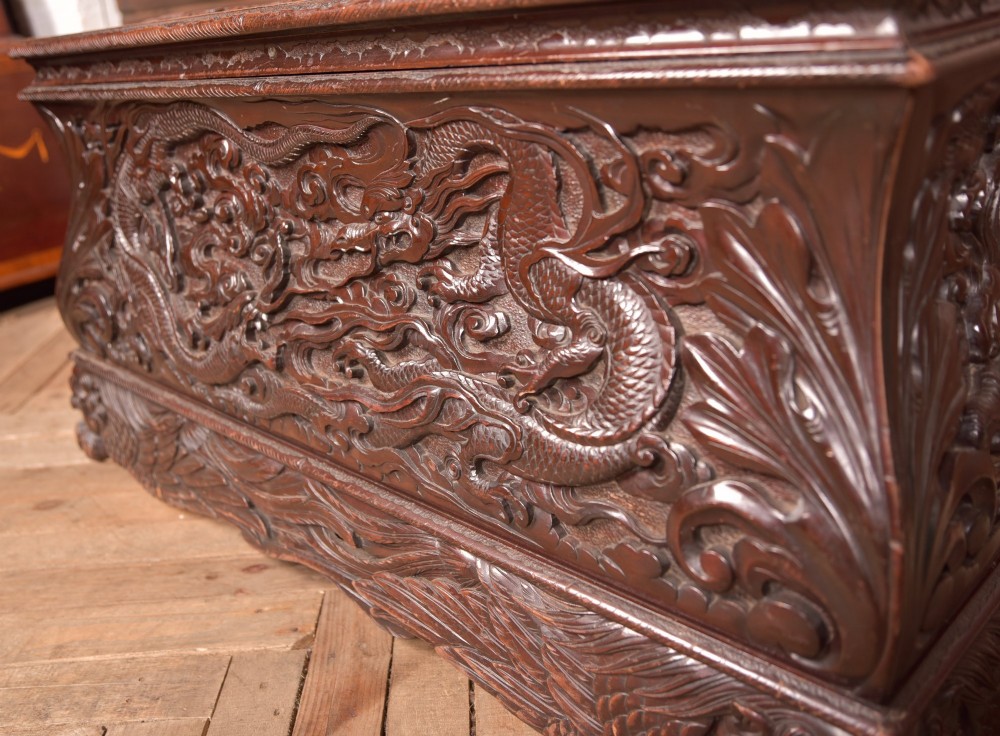A dark brown rectangular carved hardwood storage chest decorated with high-relief dragon and cloud motifs on all visible faces. View V