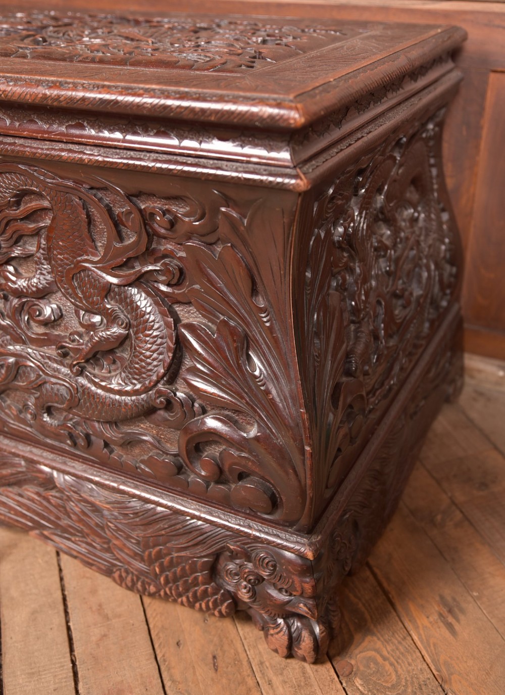 A dark brown rectangular carved hardwood storage chest decorated with high-relief dragon and cloud motifs on all visible faces. View VI