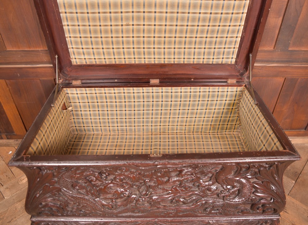 A dark brown rectangular carved hardwood storage chest decorated with high-relief dragon and cloud motifs on all visible faces. View VII