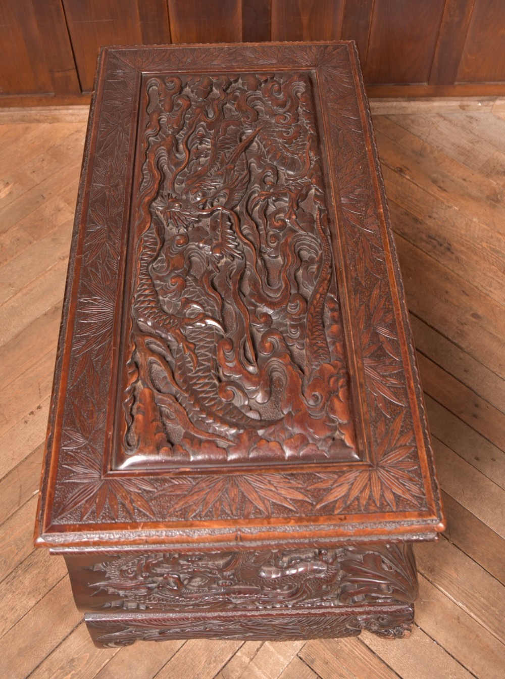 A dark brown rectangular carved hardwood storage chest decorated with high-relief dragon and cloud motifs on all visible faces. View XII
