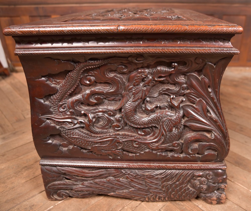 A dark brown rectangular carved hardwood storage chest decorated with high-relief dragon and cloud motifs on all visible faces. View XIII