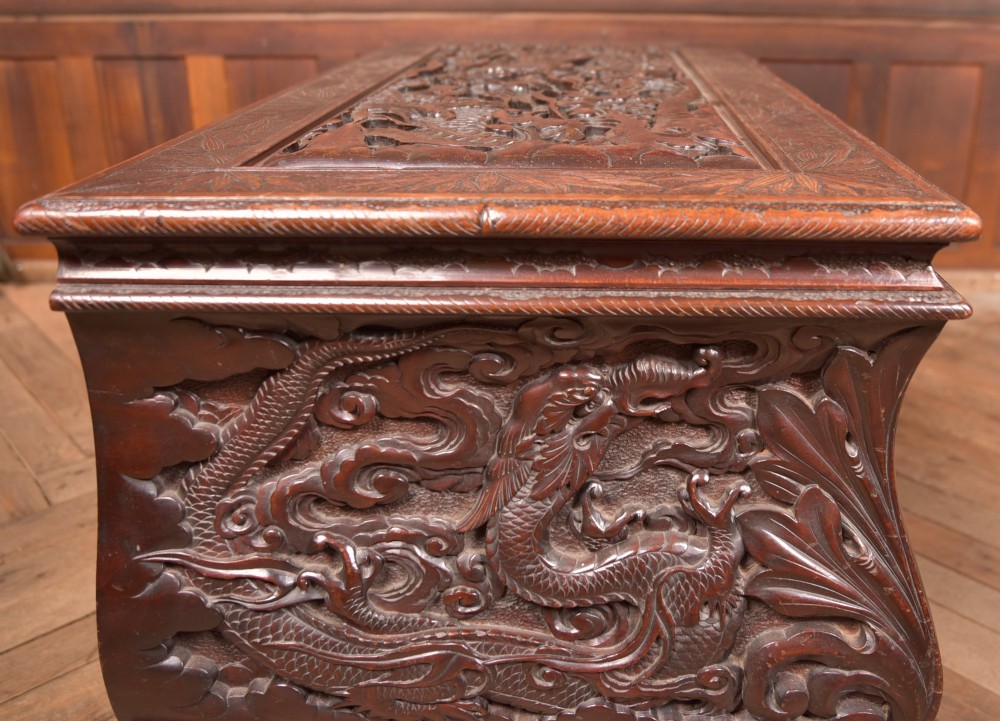 A dark brown rectangular carved hardwood storage chest decorated with high-relief dragon and cloud motifs on all visible faces. View XIV