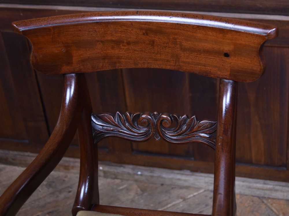 A Victorian metamorphic mahogany childs high chair with turned legs, curved armrests, a carved backrest crest, and cream fabric upholstery. View III