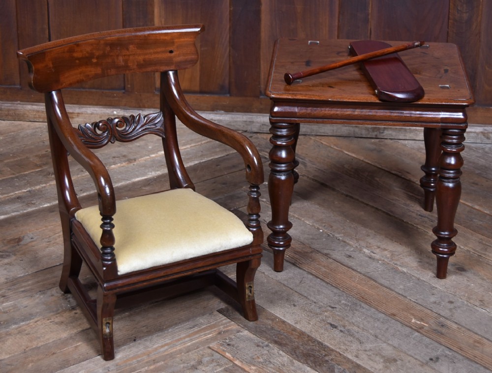 A Victorian metamorphic mahogany childs high chair with turned legs, curved armrests, a carved backrest crest, and cream fabric upholstery. View XII