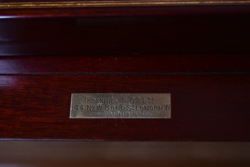 An Edwardian mahogany drinks cabinet table featuring hinged folding top leaves, a rising central tray mechanism, satinwood inlay, and turned legs on brass castors. View IV