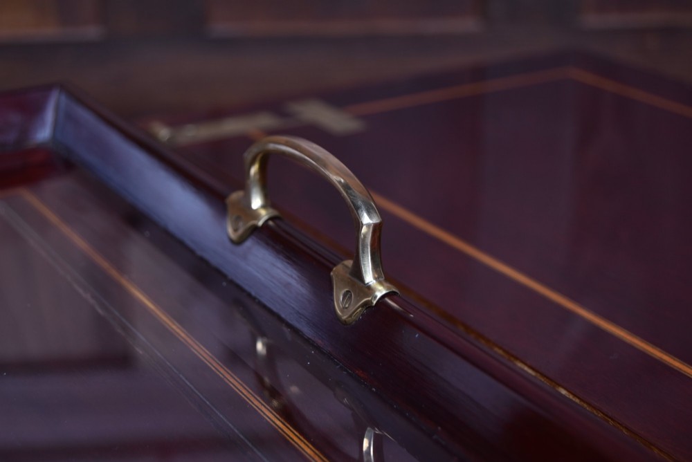 An Edwardian mahogany drinks cabinet table featuring hinged folding top leaves, a rising central tray mechanism, satinwood inlay, and turned legs on brass castors. View V