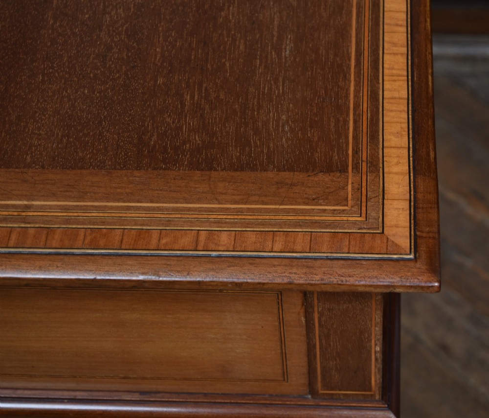 An Edwardian mahogany drinks cabinet table featuring hinged folding top leaves, a rising central tray mechanism, satinwood inlay, and turned legs on brass castors. View XIII