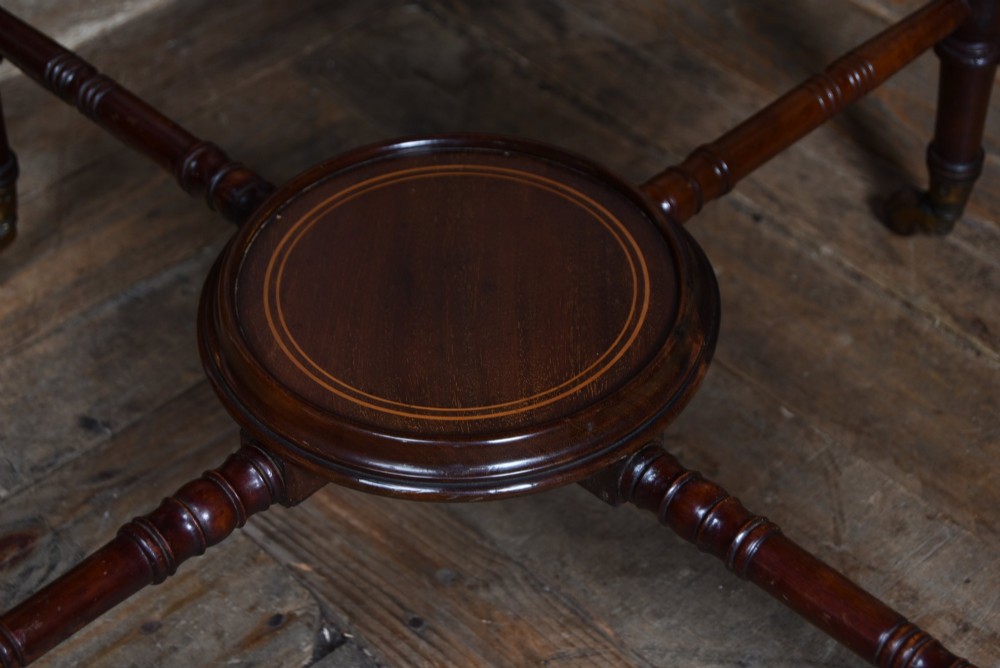 An Edwardian mahogany drinks cabinet table featuring hinged folding top leaves, a rising central tray mechanism, satinwood inlay, and turned legs on brass castors. View XV