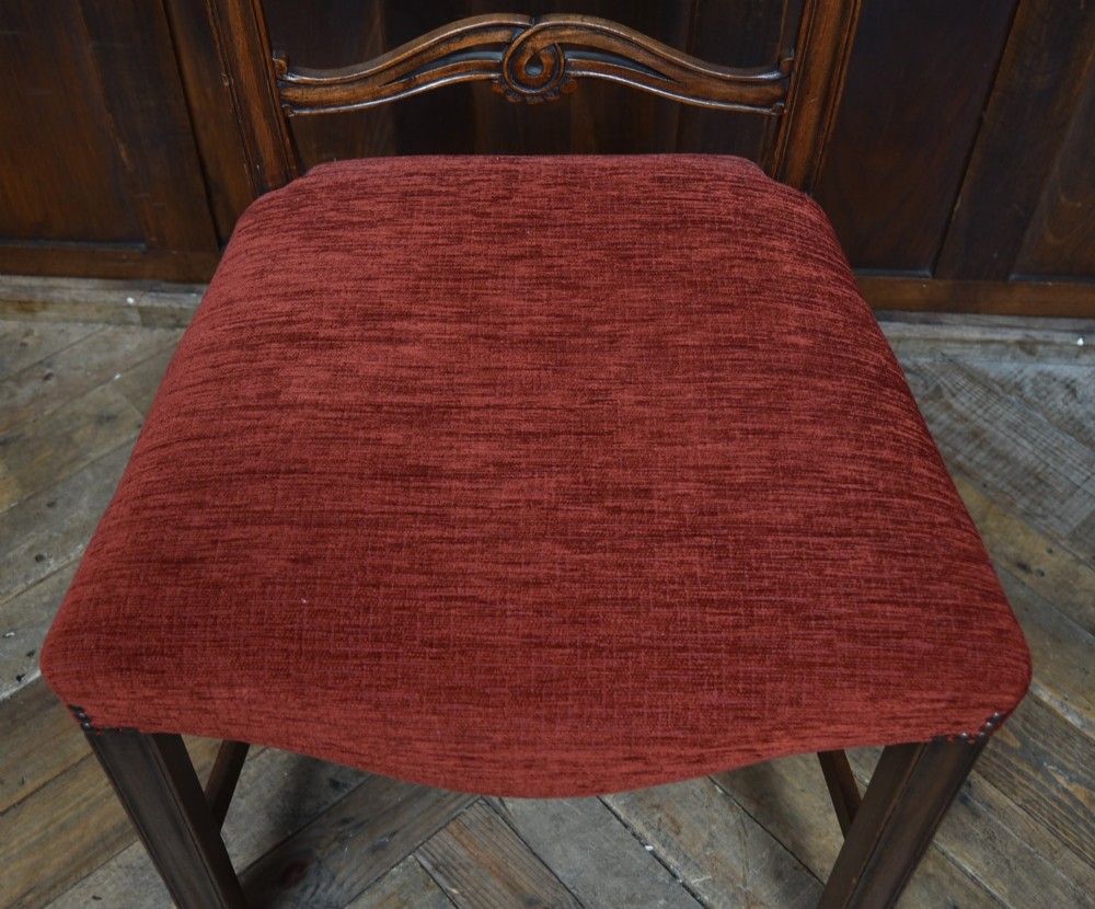 A set of Chippendale Revival mahogany dining chairs featuring carved ladder-back splats and red upholstered seats. View IV