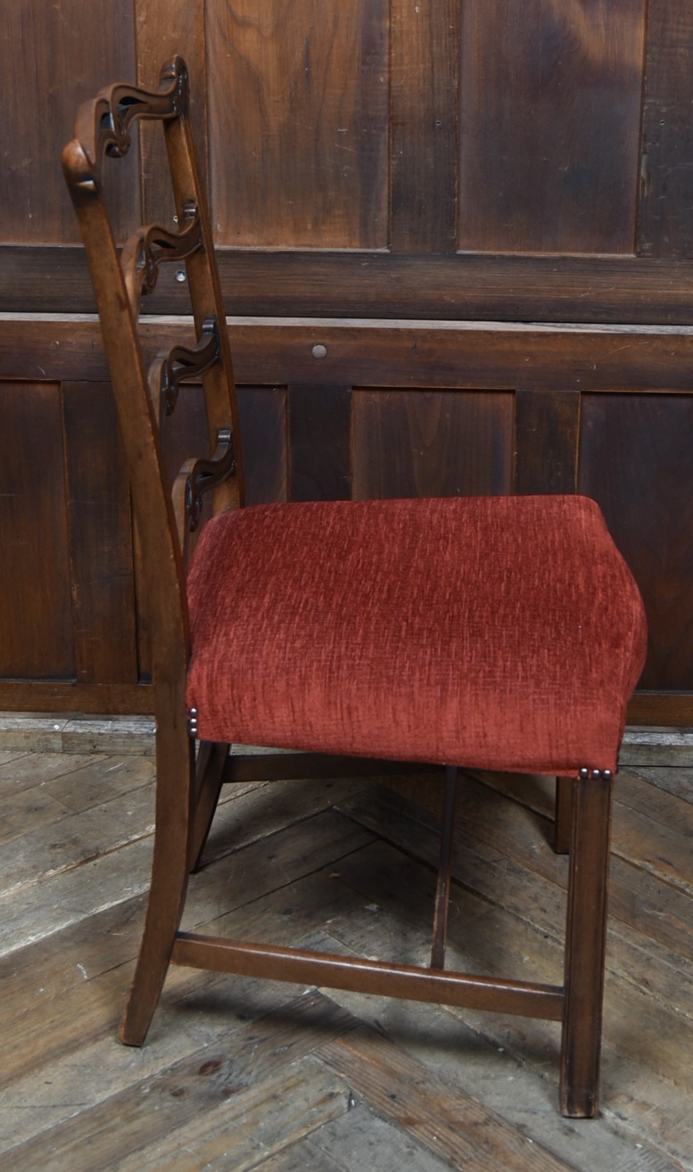 A set of Chippendale Revival mahogany dining chairs featuring carved ladder-back splats and red upholstered seats. View V