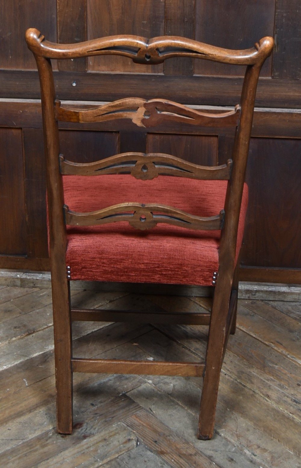 A set of Chippendale Revival mahogany dining chairs featuring carved ladder-back splats and red upholstered seats. View VI