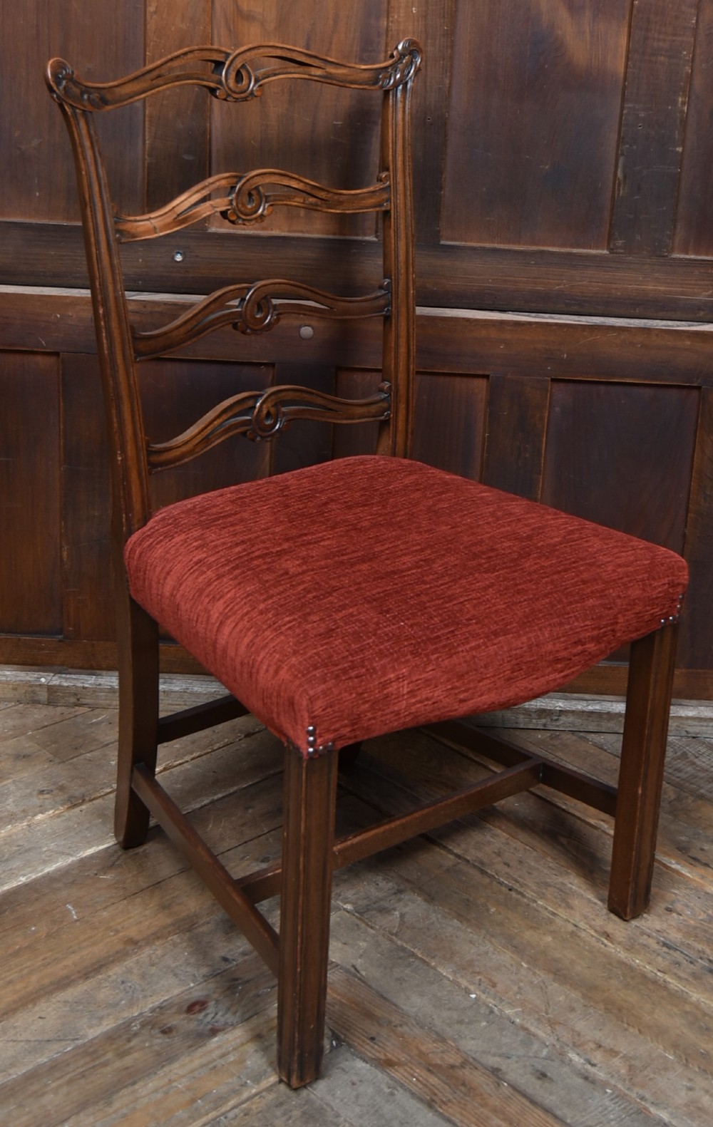 A set of Chippendale Revival mahogany dining chairs featuring carved ladder-back splats and red upholstered seats. View XV