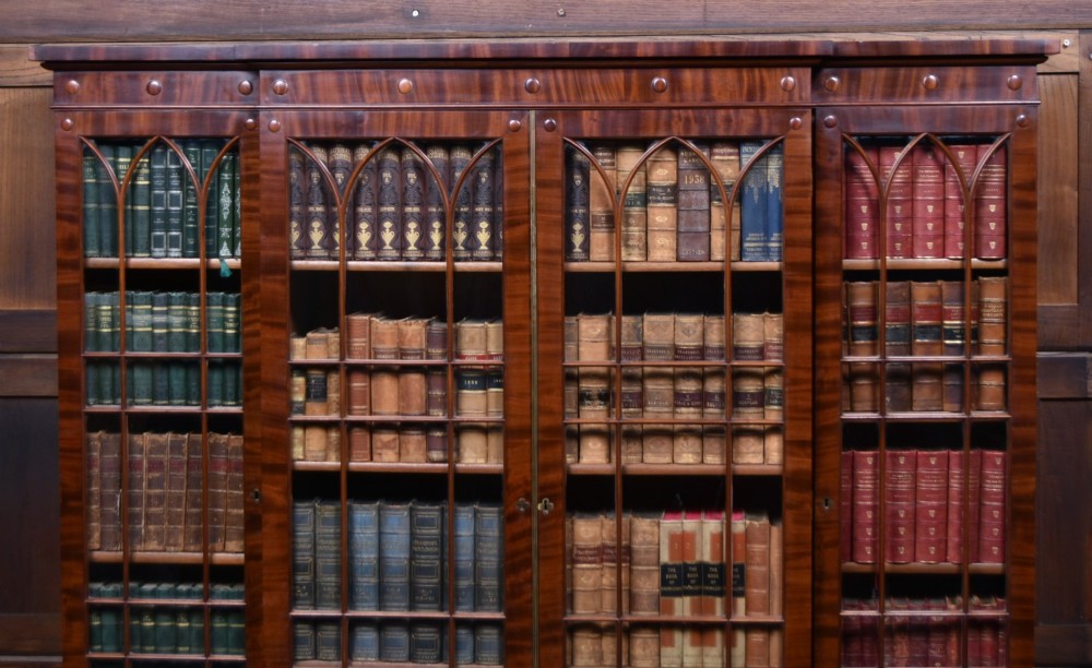 A large 19th-century flame mahogany secretaire bookcase featuring four glazed upper doors with arched astragal glazing, above a drop-down desk compartment fitted with drawers and a green writing surface. View II