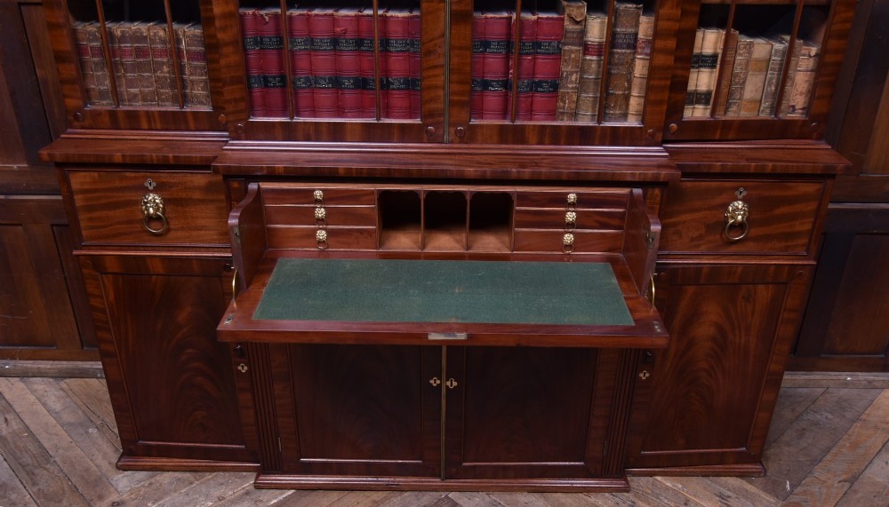 A large 19th-century flame mahogany secretaire bookcase featuring four glazed upper doors with arched astragal glazing, above a drop-down desk compartment fitted with drawers and a green writing surface. View IV