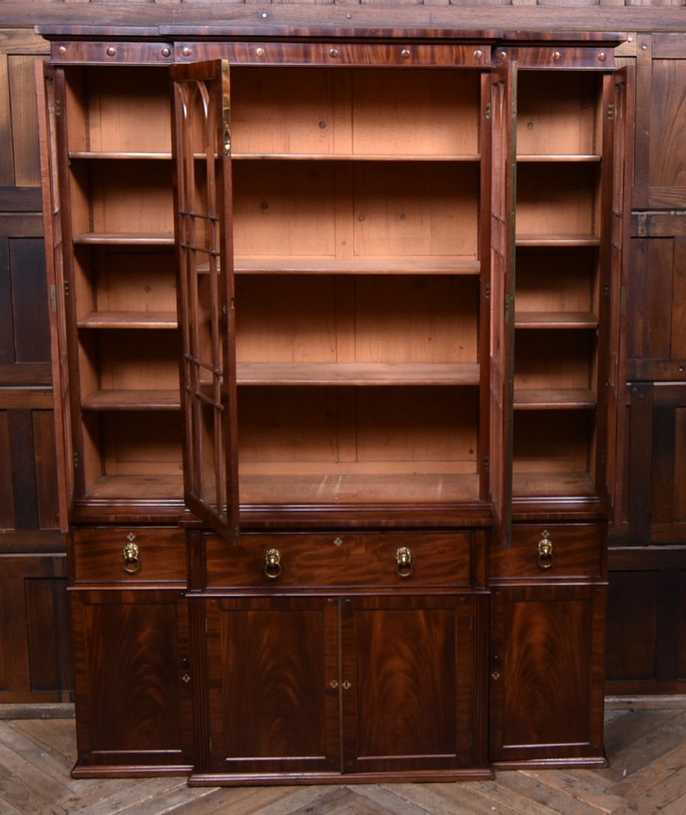 A large 19th-century flame mahogany secretaire bookcase featuring four glazed upper doors with arched astragal glazing, above a drop-down desk compartment fitted with drawers and a green writing surface. View VIII